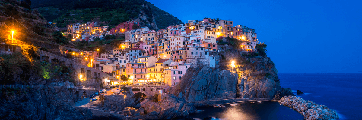 Grupo de viajeros explorando un pueblo pintoresco de Cinque Terre con casas de colores junto al mar, ideal para un viaje solo en grupo.